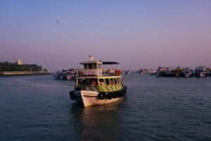 A ferry boat traveling down a river next to a city